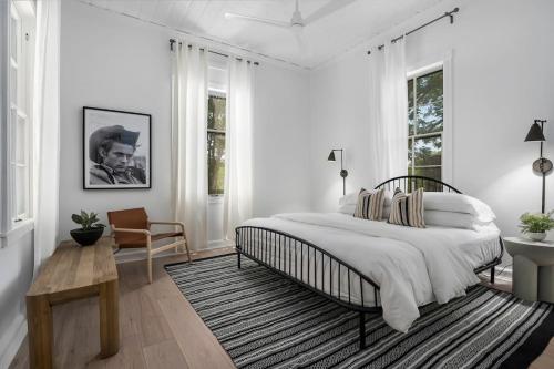a white bedroom with a bed and a chair at The Ressman Haus at MarktPlatz with Hot Tub in Fredericksburg