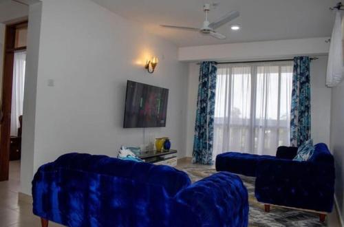 uma sala de estar com dois sofás azuis e uma televisão em Modern 1bedroom 5 min walk to the beach near Severine Neptune beach resort behind go kart em Mombasa