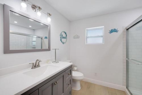 a bathroom with a sink and a mirror and a toilet at Gorgeous Beach Condo with Pool Spa and Bikes in Fort Myers Beach