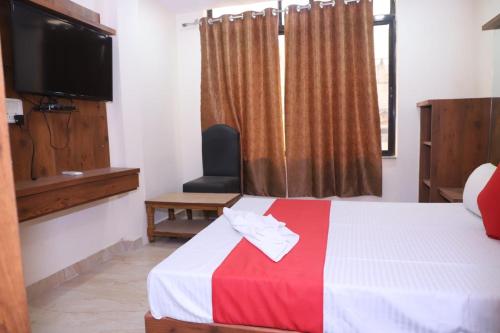 a hotel room with a bed with a television and a window at TRP Rama Inn in Gwalior