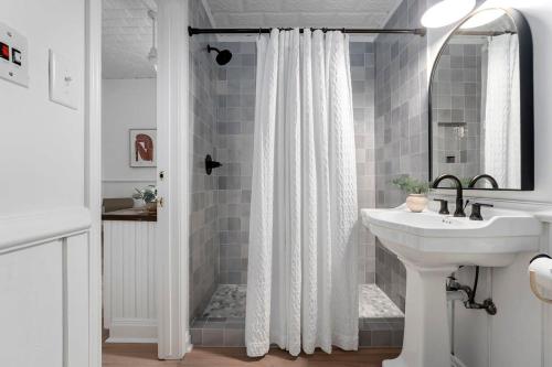 Un baño con una cortina de ducha blanca y un lavabo. en The Ressman Compound for Big Groups plus Hot tub, en Fredericksburg