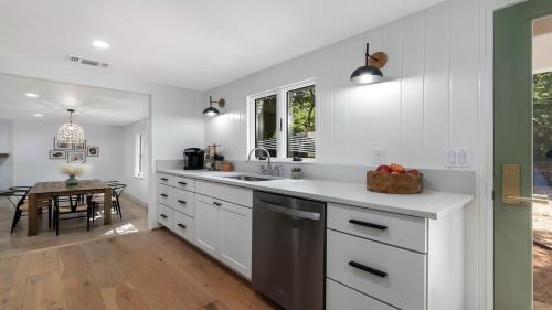 een keuken met witte kasten, een wastafel en een tafel bij Cava House, Hot tub, Cowboy Pool, Fire pit! in Fredericksburg