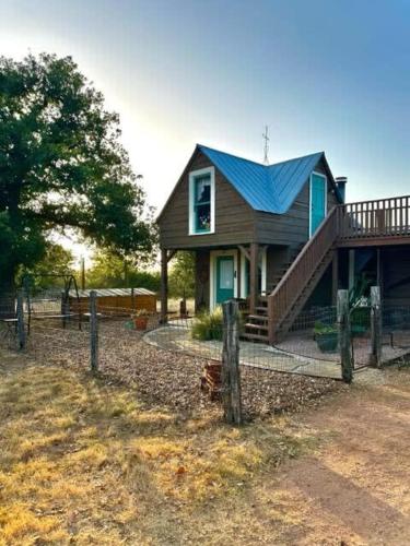 een klein huis met een blauw dak en een hek bij Das Jager Haus Secluded Cabin pet friendly in Fredericksburg