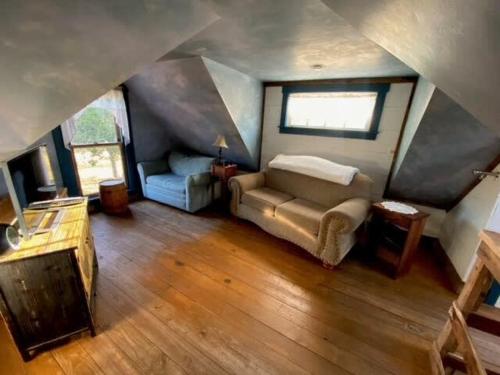 een slaapkamer met een bank en een stoel op zolder bij Das Jager Haus Secluded Cabin pet friendly in Fredericksburg