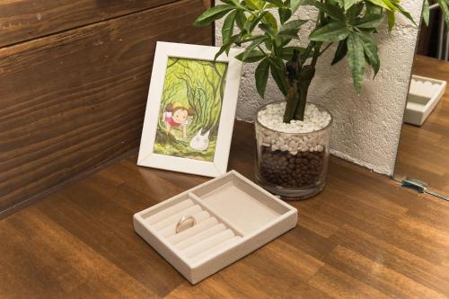 a table with a plant and a picture and a box at ガジュマルの庭～itoman in Ō