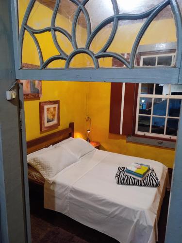 Cama pequeña en habitación con ventana en Casa Centenária localizada no coração da cidade, en São Luís do Paraitinga