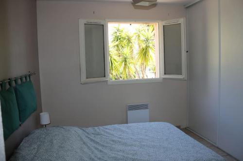 - une chambre avec un lit et une fenêtre avec un palmier dans l'établissement Agréable villa - proche commodités mer et montagne, à Afa