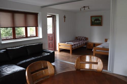 a living room with a black couch and wooden chairs at Dom na Cichej in Krasnobród