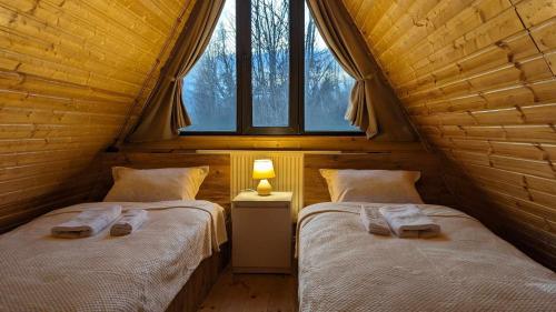 two beds in a wooden room with a window at Horizon Racha in Ambrolauri