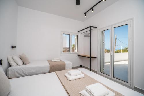 a white bedroom with two beds and a balcony at Montis villa in Daratso