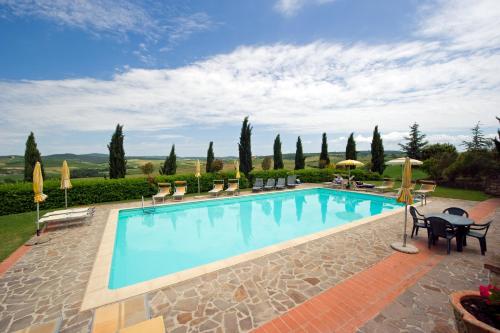 a large swimming pool with chairs and umbrellas at Agriturismo Palazzo Conti - B in Pienza