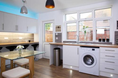a kitchen with a sink and a washing machine at Stunning 4br House for 10 Near Beach w Hot Tub in Bognor Regis