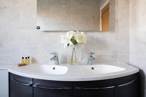 a bathroom sink with a vase of flowers on it at Stunning 4br House for 10 Near Beach w Hot Tub in Bognor Regis