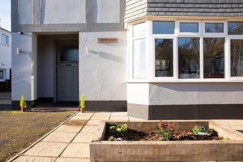 a house with a flower bed in front of it at Stunning 4br House for 10 Near Beach w Hot Tub in Bognor Regis