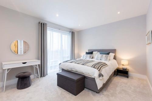 a white bedroom with a bed and a mirror at Stylish new home with parking - king beds garden in Chichester