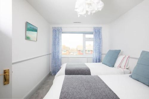 a white bedroom with a bed and a window at Bright & modern Sussex seafront home Great views in Selsey