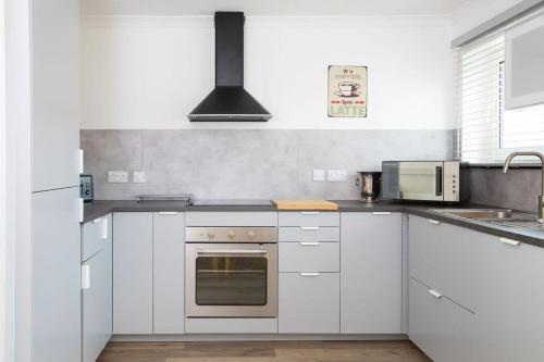 a kitchen with white cabinets and a stove top oven at Bright & modern Sussex seafront home Great views in Selsey