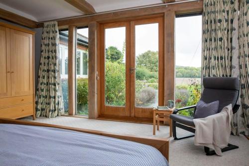 a bedroom with a bed and a chair and windows at Stunning Cottage in South Downs National Park in Eartham