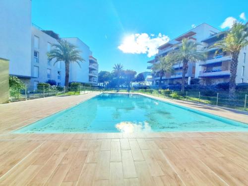 - une piscine bordée de palmiers et de bâtiments dans l'établissement Spacieux T3-Toit terrasse-Clim-wifi-piscine, à Fréjus