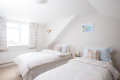 2 camas en una habitación blanca con ventana en Seaside detached 4bd home nr shops Parking Garden en West Wittering
