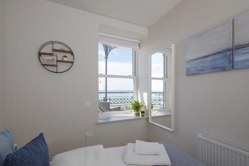 a bedroom with a bed and a window with a view of the ocean at Panoramic sea views in beachfront apt w balcony in Bognor Regis