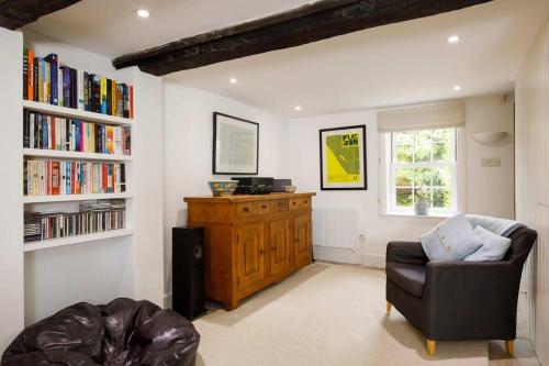 a living room with a chair and a book shelf at Country cottage in pretty village quay views in Chichester