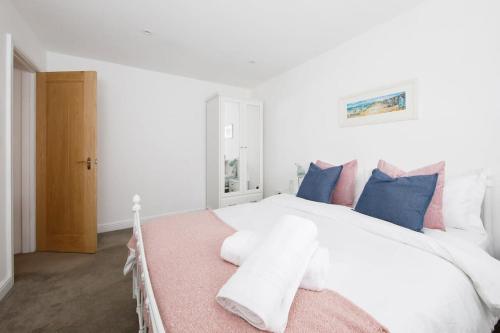 a bedroom with a white bed with blue and pink pillows at Idyllic countryside annexe near West Wittering beach in West Wittering