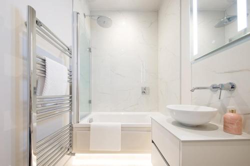 a white bathroom with a sink and a tub at Panoramic sea views in beachfront apt w balcony in Bognor Regis