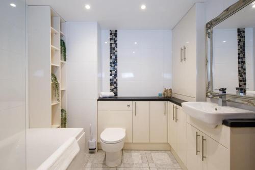 a white bathroom with a sink and a toilet and a tub at Idyllic countryside annexe near West Wittering beach in West Wittering