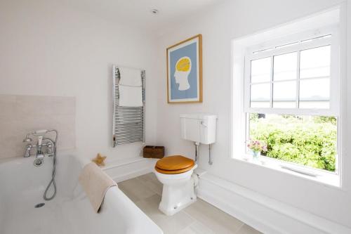 a white bathroom with a toilet and a window at Country cottage in pretty village quay views in Chichester