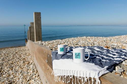 two coffee mugs sitting on a blanket on a beach at Panoramic sea views in beachfront apt w balcony in Bognor Regis