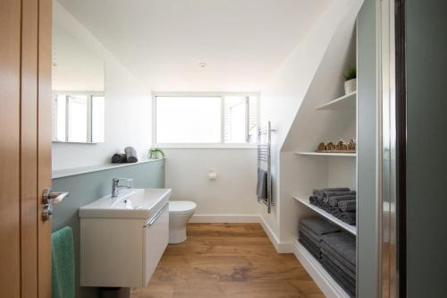 uma casa de banho com um WC branco e um lavatório. em Surfer's Paradise Steps to Beach Sleek&Stylish em East Wittering