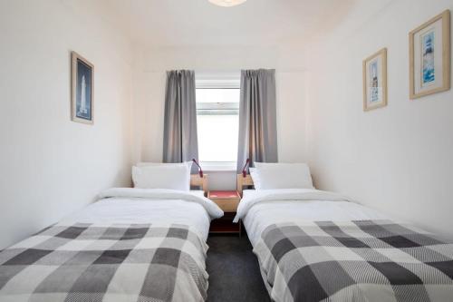 two beds in a room with a window at Stunning Beachfront Apt w Balcony & Sea Views in Bognor Regis