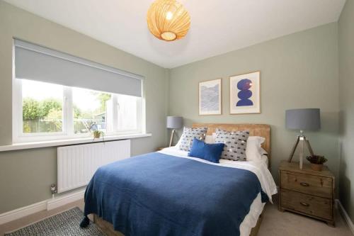 Un dormitorio con una cama azul y una ventana en Bosham 3 BR Beach House with Garden & Playhouse en Chichester