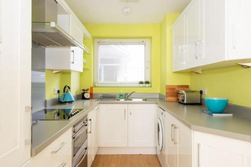 a kitchen with white cabinets and a window at Sunny & Modern Near the Beach & Village w Parking in East Wittering