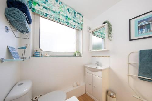 a bathroom with a toilet and a sink and a window at Sunny & Modern Near the Beach & Village w Parking in East Wittering