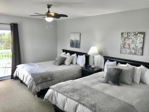 a bedroom with two beds and a ceiling fan at Stay in Gros Morne in Rocky Harbour