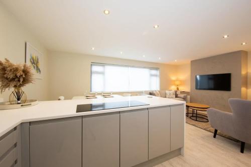 a kitchen with white cabinets and a living room at Designer Family Escape Hot Tub Steps to Beach in East Wittering