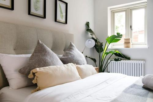 a bedroom with a white bed with pillows and a plant at Stylish Self-Contained Countryside Accommodation in Chichester