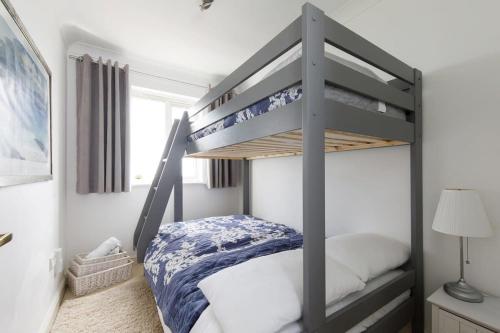 a bedroom with a bunk bed with blue and white sheets at Wonderful Seafront Home - Panoramic Ocean Views in Selsey