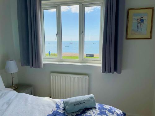 a bedroom with a window with a view of the beach at Wonderful Seafront Home - Panoramic Ocean Views in Selsey