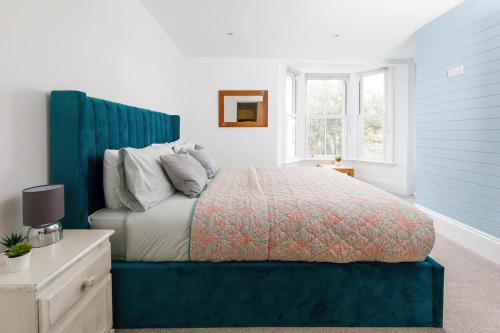 a bedroom with a large bed with a blue headboard at Lovely Seaside Villa & Gardens 40 Metres to Beach in Felpham