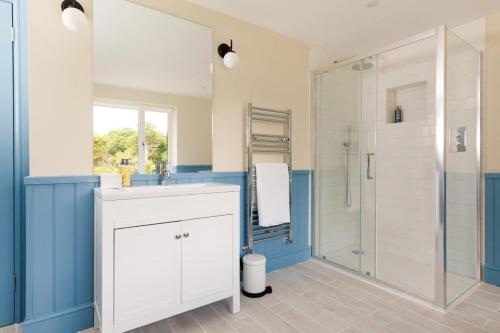 a bathroom with a sink and a shower at Stunning 5BR Home with Pool - 5 min to Beach in West Wittering