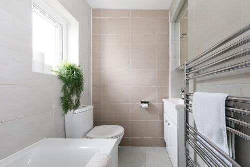 a bathroom with a toilet and a plant on top of it at Lovely Seaside Villa & Gardens 40 Metres to Beach in Felpham