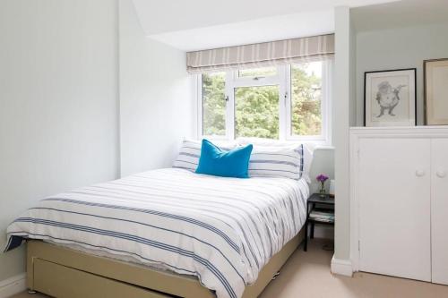 a white bedroom with a bed with blue pillows at Stunning 5BR Home with Pool - 5 min to Beach in West Wittering