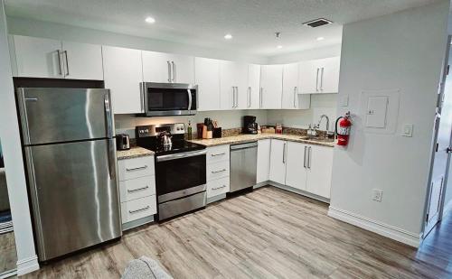 a kitchen with white cabinets and a stainless steel refrigerator at The Lofts on Clematis 202 Downtown West Palm Beach in West Palm Beach