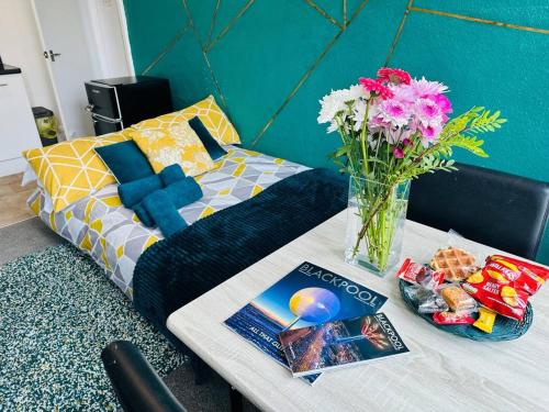 a bed with a vase of flowers on a table at Luminous Suites in Blackpool