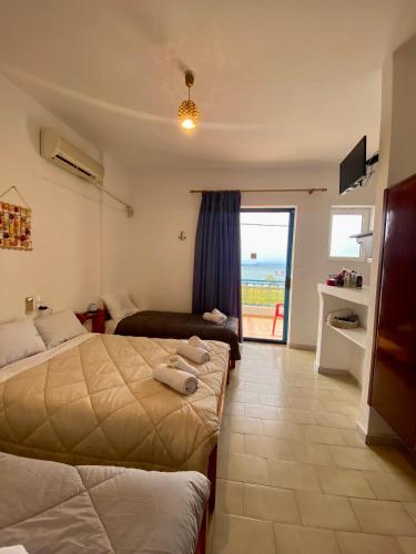 a bedroom with two beds and a view of the ocean at Alexandra Studios in Néos Pírgos