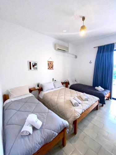 two beds in a room with blue curtains at Alexandra Studios in Néos Pírgos
