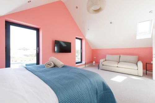 een slaapkamer met rode muren en een bed en een bank bij Luxury designer coastal home for 10 with hot tub in West Wittering